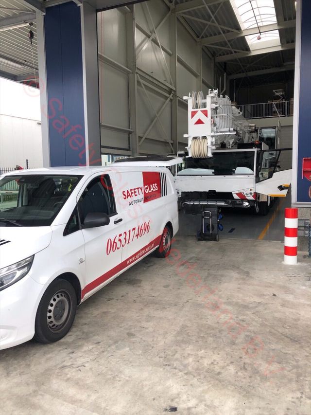 Servicebus van Safety Glass in de werkplaats, met een werkvoertuig op de achtergrond