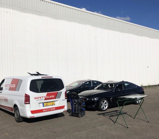 Nieuwe voorruit op een glasstandaard naast de auto waarin hij geplaatst wordt